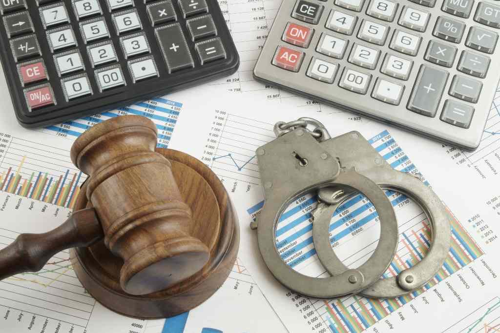A gavel, handcuffs, and a calculator on a financial report symbolize the justice system's involvement in financial matters.