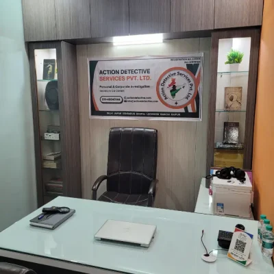 A laptop on a desk with a chair in front of a wall.